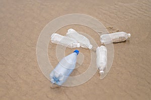 Plastic water bottles on the sandy shore of the ocean. Environmental pollution with waste. Environmental and social issues. There