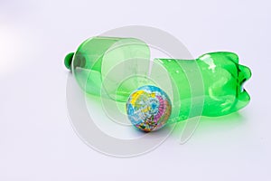 Plastic water green bottle cut in half  placed behind the blue globe. Concept of global warming and recycling.