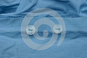 Plastic white buttons on a piece of blue cloth shirt