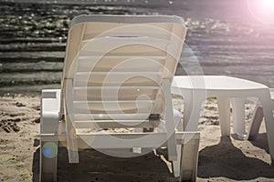 Plastic white chaise lounges on the empty beach of the riverbank