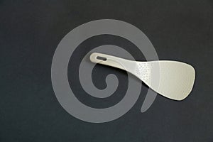 Plastic white spoon for multicooker on a dark background close-up
