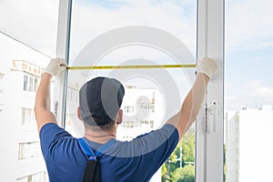 A plastic window installation worker measures the light opening of a window using roulette photo