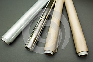 Plastic wrap, aluminum foil and roll of parchment paper on grey background