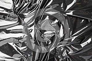 Plastic wrap. Black shiny film bag pattern. Transparent dark cellophane texture. Creative crumpled background