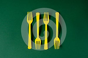 Plastic yellow forks on a green background