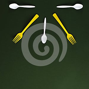Plastic yellow forks and white spoons on a green background