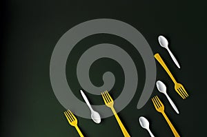 Plastic yellow forks and white spoons on a green background.