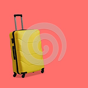 Plastic Yellow suitcase isolated on pink background. Suitcase with wheels and retractable telescopic handle. Travel