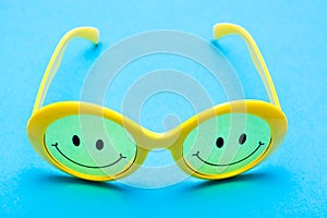 Plastic yellow sunglasses with painted eyes and a smile on the glass