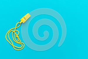 Plastic yellow whistle on turquoise blue background