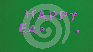 Plasticine inscription Happy Easter in purple color on a green background. Chromakey plasticine inscription