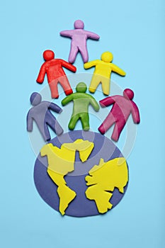 Plasticine multicolored cartoon people on globe. The use and depletion of the planet earth, overpopulation and population growth