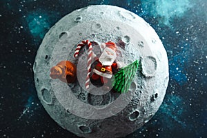 Plasticine Santa Claus lies on the moon with a bag of gifts and a Christmas tree