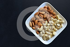 Plate with almond and cashew - top view with isolated in black b