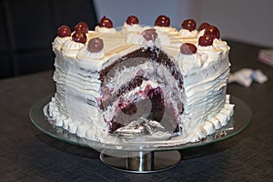 Plate with authentic Black Forest Cake Schwarzwalder kirsch cake decorated with whipped cream and cherries