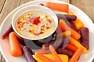 Plate of baby rainbow carrots with hummus close up