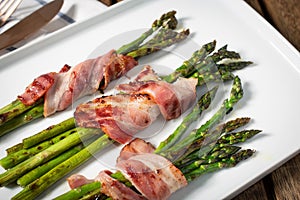 Cooked asparagus with wrapped bacon on plate photo