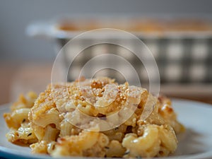Plate of baked macaroni and cheese in front of a casserole dish