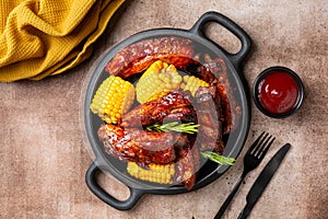 Plate with baked pork ribs with corn cobs, barbecue sauce, rosemary.