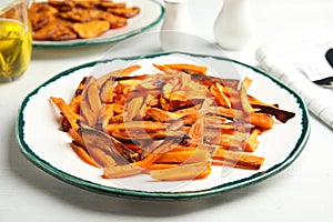 Plate with baked sweet potato slices on table