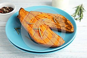 Plate with baked sweet potato on white wooden table