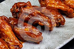 Plate of barbecue chicken wings on black background