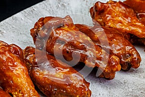 Plate of barbecue chicken wings on black background