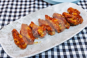 Plate of barbecued chicken wings on a black and white checkered tablecloth