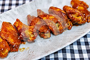 Plate of barbecued chicken wings on a black and white checkered tablecloth