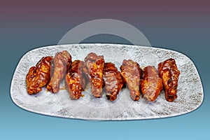 Plate of barbecued chicken wings on a magenta and light blue gradient background