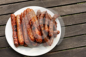 Plate of barbequed sausages on wooden table