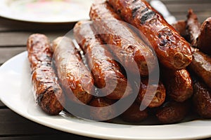 Plate of barbequed sausages on wooden table