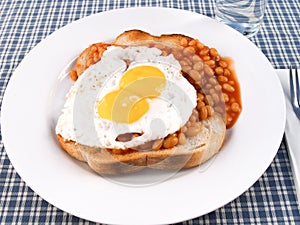 A plate of beans on toast with a double yolk egg