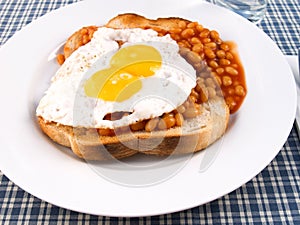 A plate of beans on toast with a double yolk egg