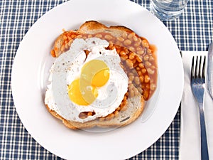 A plate of beans on toast with a double yolk egg