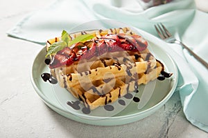 Plate with Belgian waffles with fresh strawberries drenched in chocolate topping