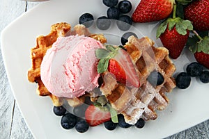 Plate of belgian waffles with strawberry ice cream, and fresh st