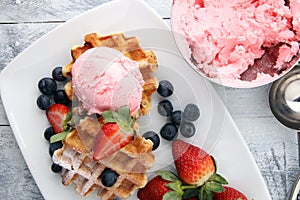 Plate of belgian waffles with strawberry ice cream, and fresh st