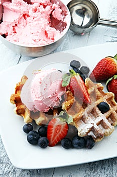 Plate of belgian waffles with strawberry ice cream, and fresh st