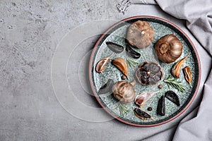 Plate with black garlic on grey table, top view. Space for