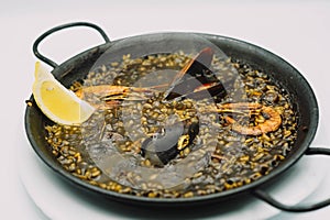 plate of black rice paella with squid, shrimp and mussels