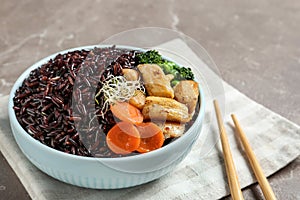 Plate of boiled brown rice with meat served on table, closeup