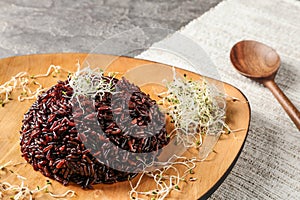 Plate of boiled brown rice with sprouted flax seeds on table.