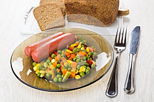Plate with boiled sausages, vegetable mix, bread on cutting boar