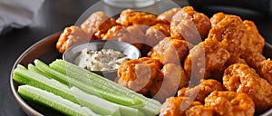 Plate of boneless chicken wings with buffalo sauce and celery sticks
