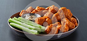 Plate of boneless chicken wings with buffalo sauce and celery sticks