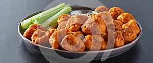 Plate of boneless chicken wings with buffalo sauce and celery sticks