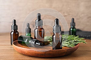 Plate with bottles of essential oils and rosemary