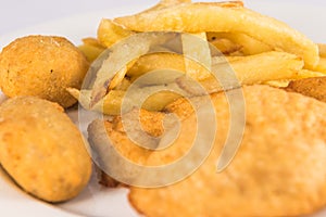 Plate of breaded chicken breast with croquettes and French fries.