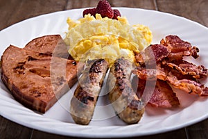 Plate of breakfast - scrambled eggs, bacon, sausage and ham 1